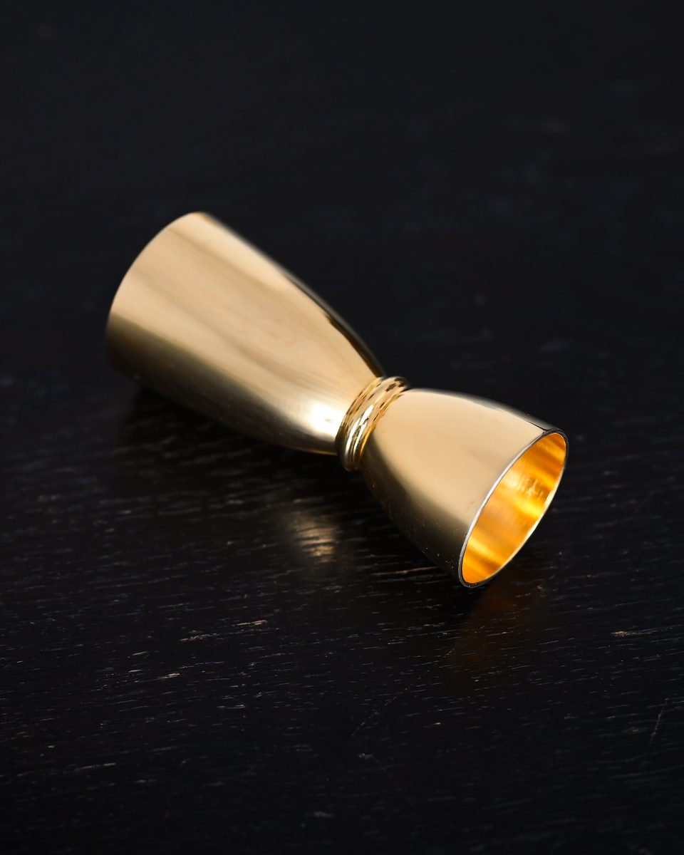Goldener Jigger auf dunklem Holz
